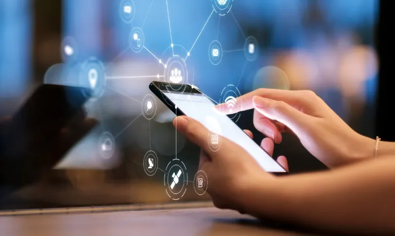 スマートフォンを操作する手とデジタルネットワークのアイコン